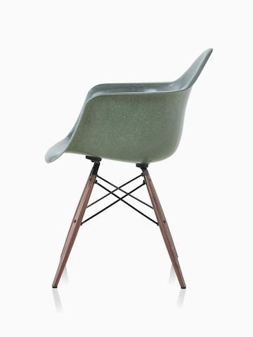Una silla de fibra de vidrio moldeada Eames en verde oscuro con descansabrazos y base de clavijas de soporte en nogal.