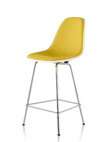 Taburete de fibra de vidrio moldeado Eames blanco con tapicería amarilla, visto desde un ángulo de 45 grados. Taburete de fibra de vidrio moldeado Eames blanco con tapicería amarilla, visto desde un ángulo de 45 grados.