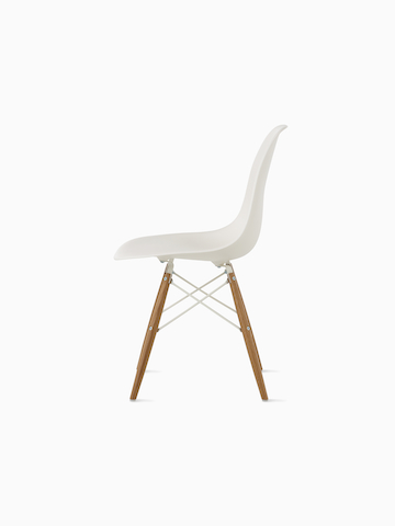 Silla de plástico blanca moldeada de Eames con una almohadilla tapizada azul y patas con clavijas, vista desde un ángulo de 45 grados.