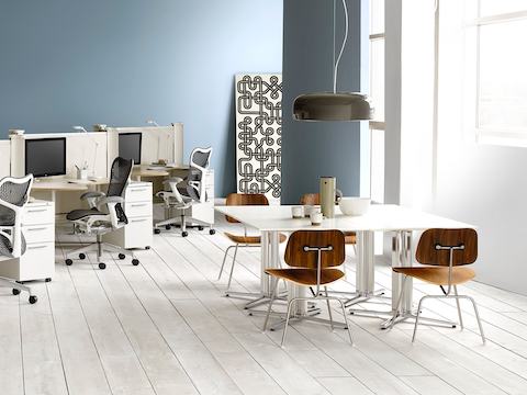 Medium-tone Eames Moulded Plywood Chairs and white Everywhere Tables in a casual meeting space.