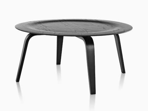 一个圆形的Eames模压胶合板咖啡桌与木腿和黑色完成缩进顶部。