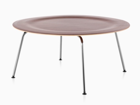 Uma mesa de café de contraplacado moldado Eames redonda com pernas de metal e um top recuado em um acabamento médio.