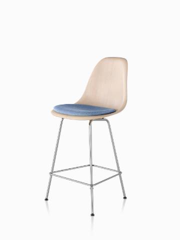 Eames从45度角观看，轻质饰面，浅蓝色座垫和银色脚的模压木凳。