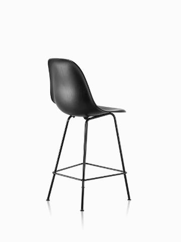 Three-quarter rear view of a black Eames Molded Wood Stool with black legs.