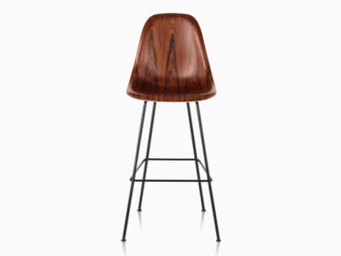 La mitad superior de un taburete de madera moldeado Eames con un acabado oscuro, visto desde el frente. La mitad superior de un taburete de madera moldeado Eames con un acabado oscuro, visto desde el frente.
