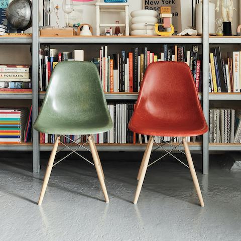 Two Eames Moulded Fibreglass Side Chairs sitting in front of a bookshelf.