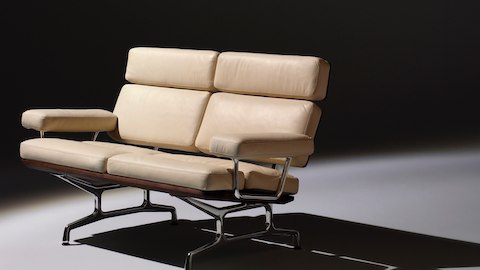 Oblique view of an ivory-colored Eames loveseat, showing the thick cushions on the seat, back, and arms. 