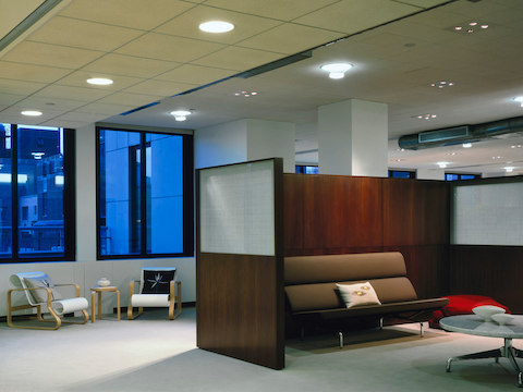 Un sofá marrón Eames compacto en un área de reunión informal parcialmente cerrada.