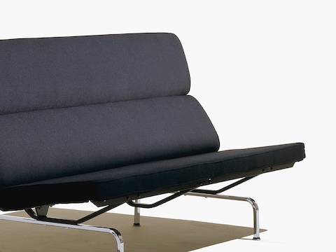 Visão angular de um sofá preto Eames Compact, com o assento de espuma e almofadas de costas e pernas de aço cromado.