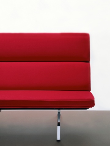 Vista frontal parcial de um vermelho Eames Sofa Compact, mostrando o estilo minimalista meados do século.