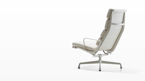 Three-quarter rear view of a white Eames Soft Pad lounge chair. Three-quarter rear view of a white Eames Soft Pad lounge chair.