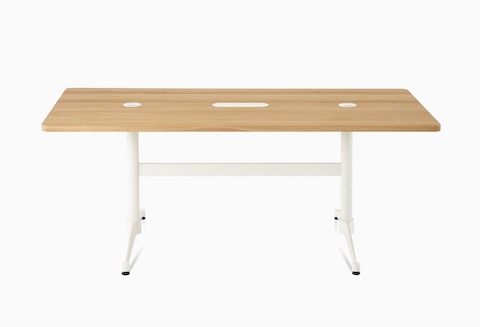 An oak Eames T-Leg Conference Table with white legs, power access, and routing capabilities.