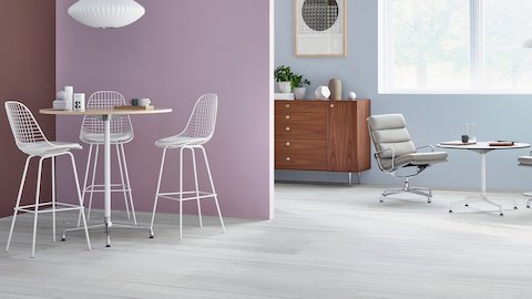 Two round Eames Tables of different heights, one served by three Eames Wire Stools and one by two gray Eames Soft Pad Chairs. Two round Eames Tables of different heights, one served by three Eames Wire Stools and one by two gray Eames Soft Pad Chairs.
