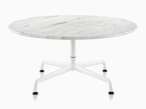 Una mesa redonda Eames al aire libre con una tapa de mármol blanco y base blanca.