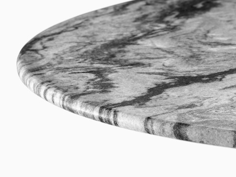 Close view of a round table top made of grey marble, one of four stones available for Eames outdoor tables. 