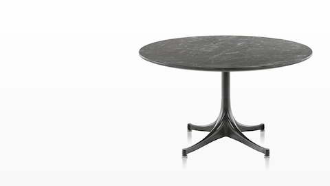 A round Eames outdoor table with a black stone top and black base. A round Eames outdoor table with a black stone top and black base.