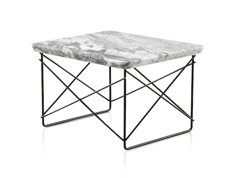 An angled view of a rectangular Eames Wire Base Low outdoor table with a marble top and black wire base. 