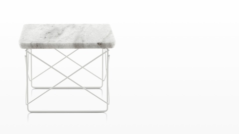 Una mesa baja de Eames Wire Base rectangular al aire libre con una tapa de mármol y una base de alambre blanco.