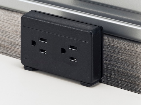 A black, two-outlet Connect Electrical Distributor attached to the back of a white work surface.