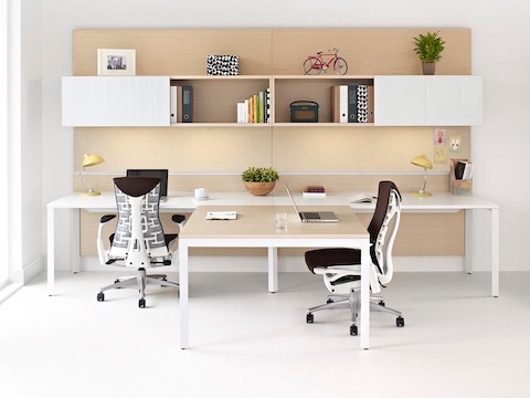 Dos sillas de oficina Embody de color rojo oscuro y una pared del equipo Canvas Office Landscape con almacenamiento superior.