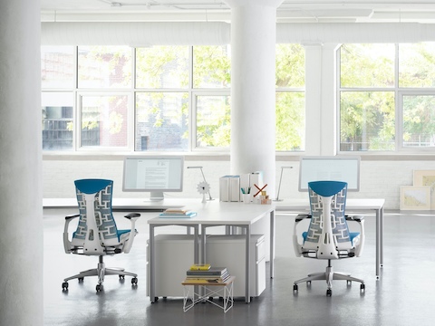 Duas cadeiras de escritório Embody azul em um ambiente de trabalho Canvas branco. Duas cadeiras de escritório Embody azul em um ambiente de trabalho Canvas branco.