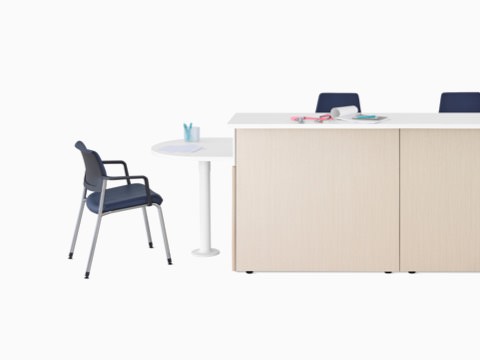 Ethospace Nurses Station in a light wood finish with transaction surface and ADA peninsula surface in white, a Verus Side Chair in blue, and Sayl Chairs in blue. Ethospace Nurses Station in a light wood finish with transaction surface and ADA peninsula surface in white, a Verus Side Chair in blue, and Sayl Chairs in blue.