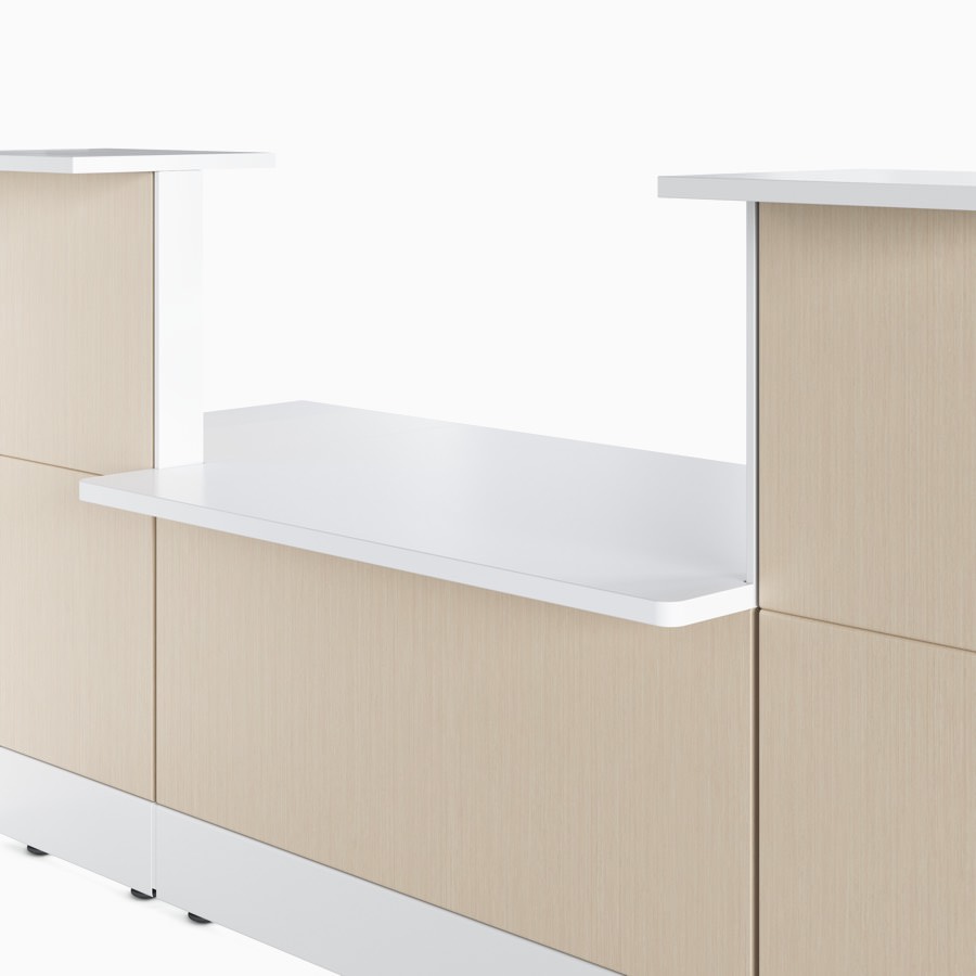 Ethospace wall unit in an ash wood finish and white trim with solid surface transaction surfaces at ADA seated height and standing height.