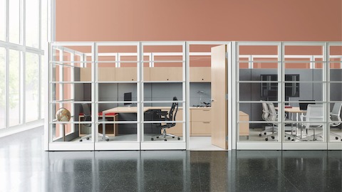 Espacio de trabajo compartido abierto con estaciones de trabajo bajas Ethospace, sillas de escritorio ergonómicas Embody grises y una sala de estar con sillones Setu cerca.