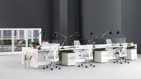 White Sayl Chairs with dark green upholstered seats at an Ethospace benching system in a bright, open office. White Sayl Chairs with dark green upholstered seats at an Ethospace benching system in a bright, open office.