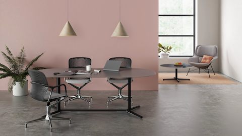 Ein offener Sitzungsbereich mit drei Keyn Stühlen um einen schwarzen Everywhere Table, dazu ein grauer Striad Stuhl an einem Tisch in Beistellhöhe.