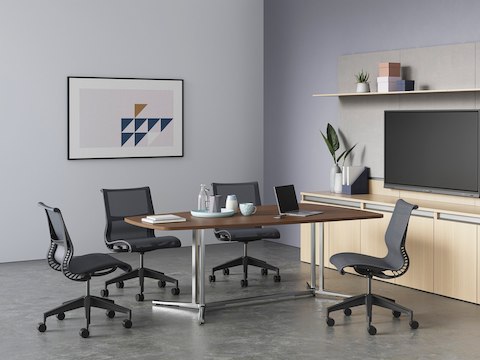 A dark wood video oval Everywhere Table arranged in a video conference environment, surrounded by four Setu Chairs.