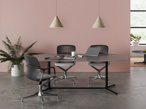 Ein offener Sitzungsbereich mit drei Keyn Stühlen um einen schwarzen Everywhere Table, dazu ein grauer Striad Stuhl an einem Tisch in Beistellhöhe.