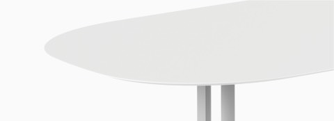 A close-up image of a white oval Everywhere Table with grey legs.