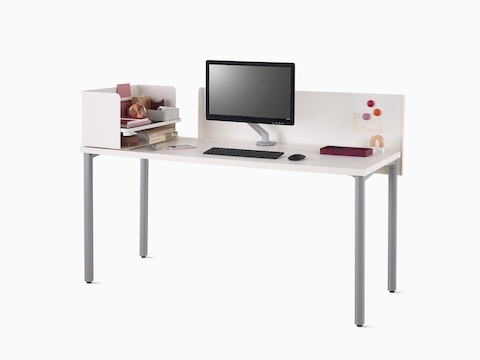 Viewed at an angle, a white Everywhere desk with a white metal privacy screen, gray legs, a Ubi organizer with notebooks, and silver Flo Monitor Arm.