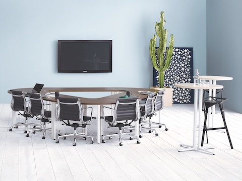 Una sala de reuniones con negro Eames Aluminum Group Sillas alrededor de Everywhere mesas de conferencias en una configuración de triángulo.