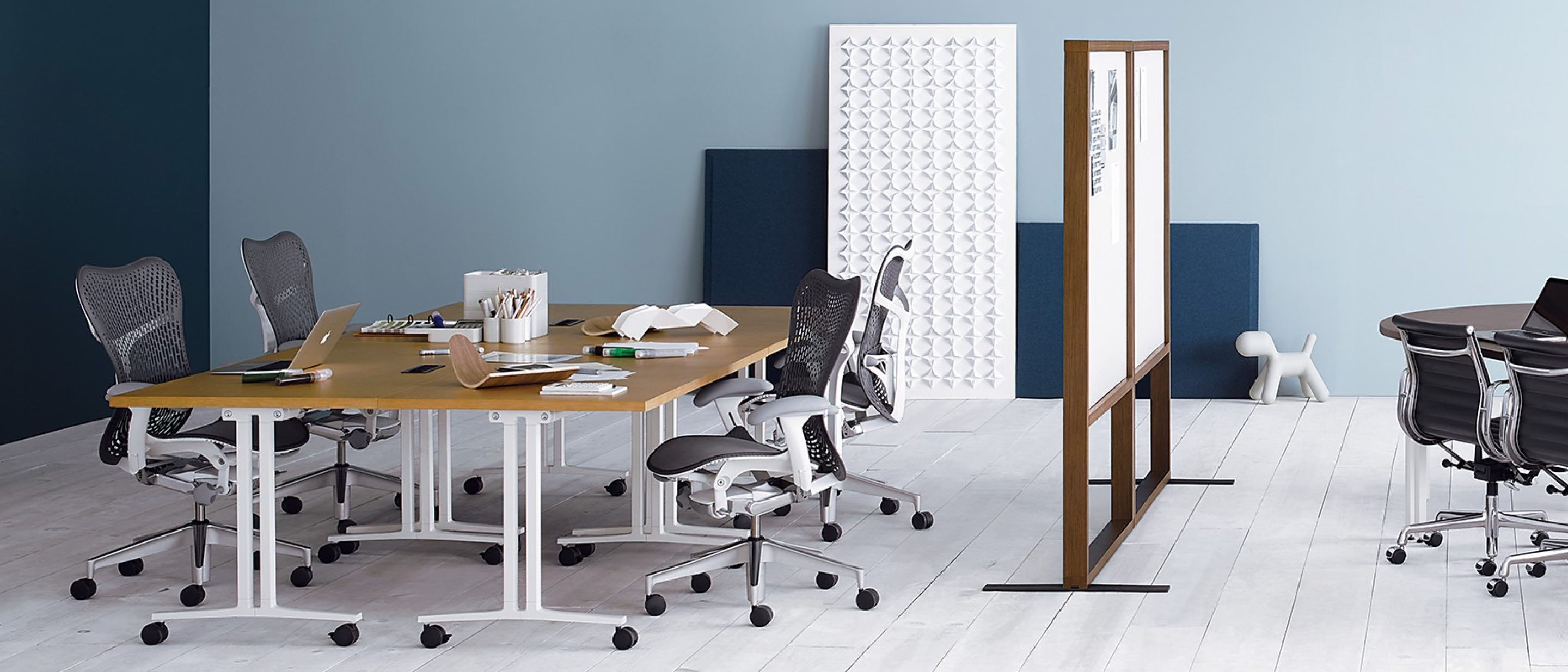 Sala com mesas Everywhere configuradas em formado de oficina à esquerda e espaço para reunião à direita.