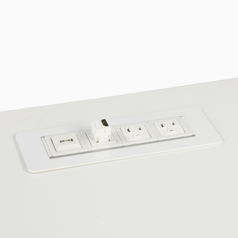 Viewed at an angle, a white HM Connect with one USB connection and three power outlets, integrated within a white work surface.