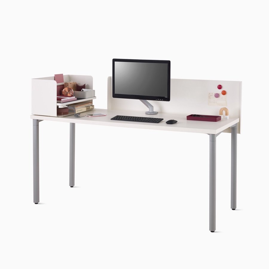 Viewed at an angle, a white Everywhere desk with a white metal privacy screen, gray legs, a Ubi organizer with notebooks, and silver Flo Monitor Arm.