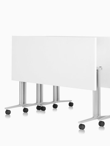 Three white Everywhere Tables, nestled together in the folded position. Select to go to the Everywhere Tables product page.