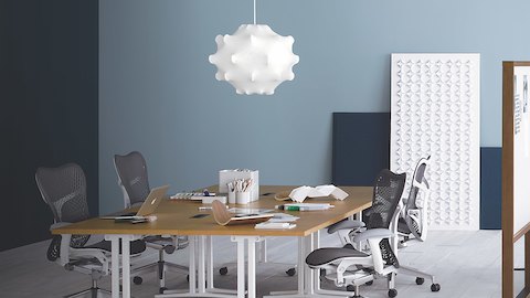 Um espaço de colaboração com cadeiras de escritório cinza Mirra 2 e quatro mesas quadradas em Everywhere, agrupadas para formar uma grande mesa de reunião.