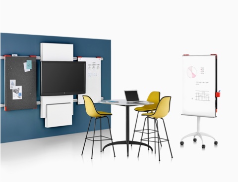 A collaboration space featuring a table, media tile, and display boards from Exclave, as well as three yellow stools.