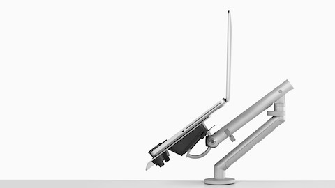 Profile view of an adjustable Flo Monitor Arm supporting an open laptop and positioned at a low angle.