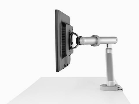 Vista de perfil de un brazo de monitor Flo conectado a la superficie que sostiene un solo monitor.