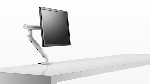 Uma visão frontal de um monitor preto fixado a um Braço para monitor Flo sobre uma mesa, incluindo o ajustador opcional Tool-less.