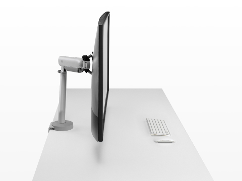 Silver single Flo X monitor arm with a 43'' screen, viewed from the side.