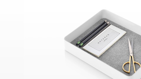 A white Formwork Short Bin with a non-skid liner holding a scissors, notepad, and pencils. A white Formwork Short Bin with a non-skid liner holding a scissors, notepad, and pencils.