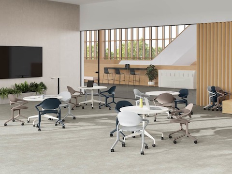 Fuld Chairs in Alpine, Nightfall, and Cocoa surround circular tables in a room with a large wall monitor and Passport table. Fuld Chairs in Alpine, Nightfall, and Cocoa surround circular tables in a room with a large wall monitor and Passport table.