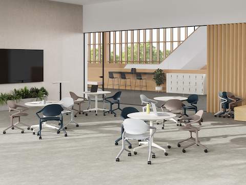 Fuld Chairs in Alpine, Nightfall and Cocoa surround circular tables in a room with a large wall monitor and Passport table. Fuld Chairs in Alpine, Nightfall and Cocoa surround circular tables in a room with a large wall monitor and Passport table.
