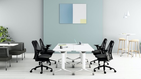 An office setting featuring a Genus flip-top tables surrounded by black Sayl office chairs and Public office landscape.