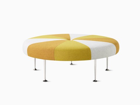 A round Girard Color Wheel Ottoman upholstered in wedges of yellow, red, and orange.